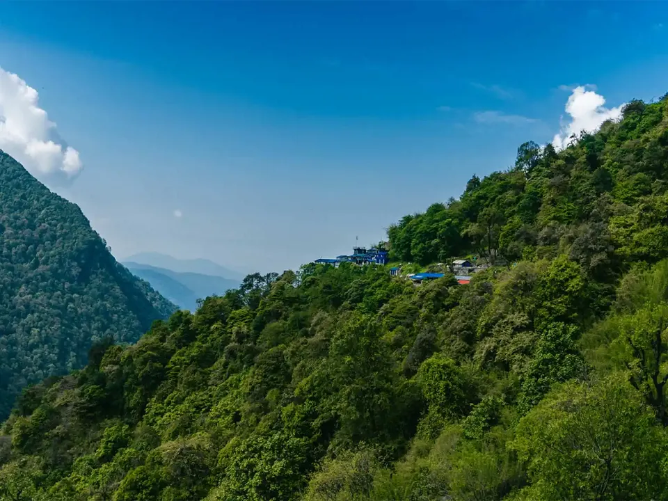 Mountain lodge perched above a forested Himalayan valley in Nepal