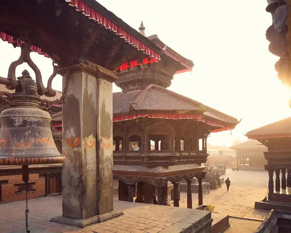 Carved temples and prayer bell in Bhaktapur Durbar Square at sunrise