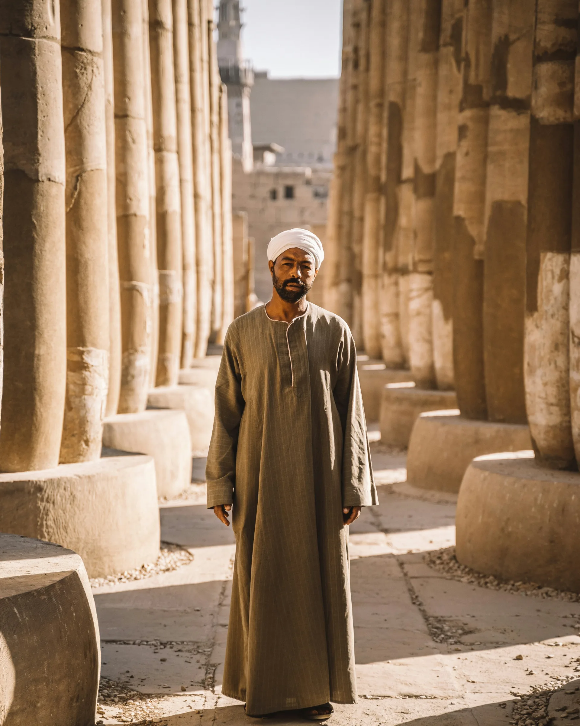 A man standing between the carved stone columns of an ancient Egyptian temple