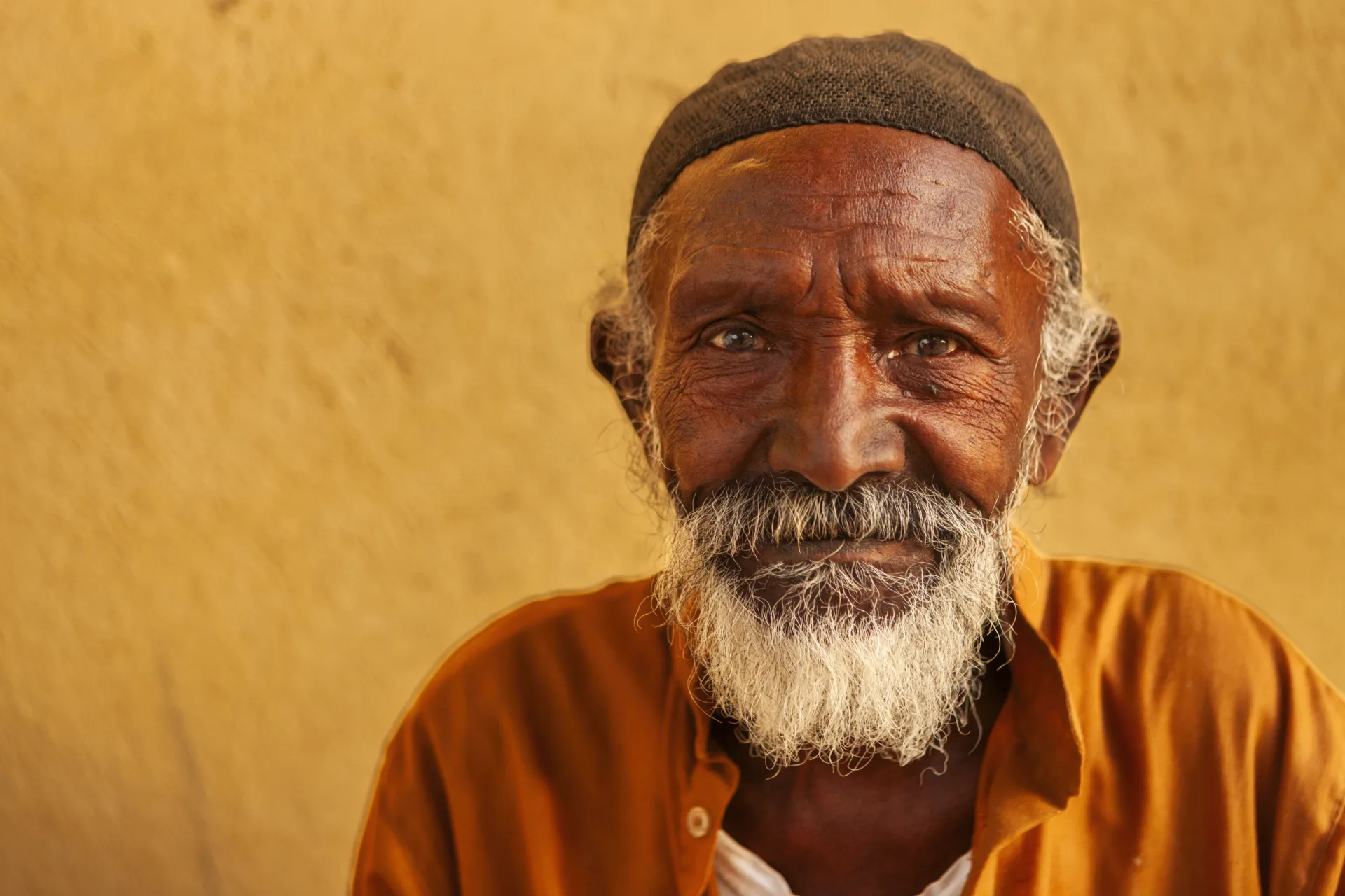 Portrait of an Egyptian man in an orange shirt against an ochre wall
