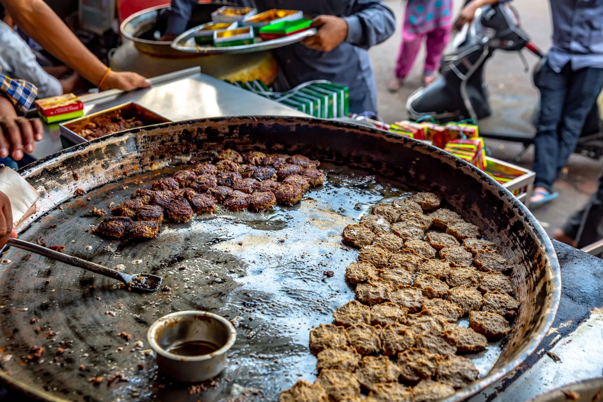 Kebabs cooking on a large griddle at a Lucknow food stall