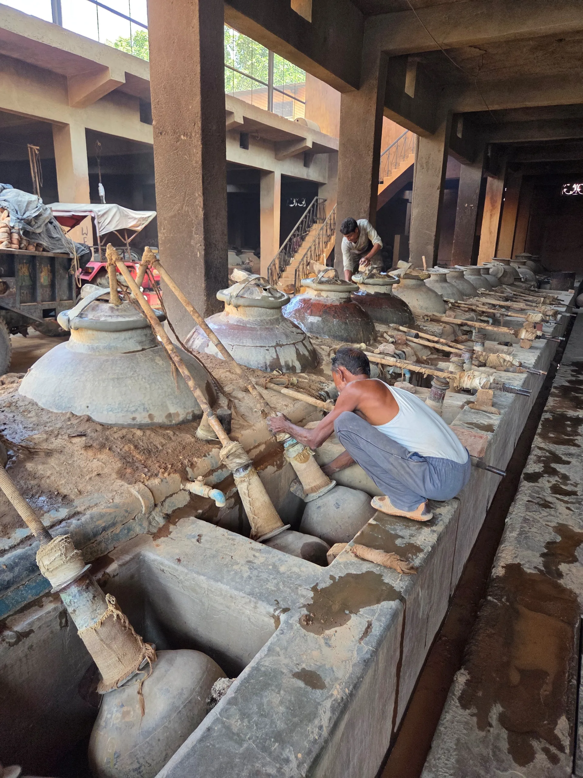 Workers tending traditional perfume distillation equipment in Kannauj