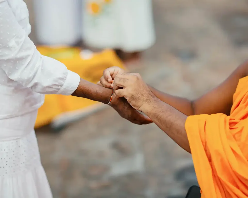 Buddhist monk tying a traditional blessing thread for a traveller