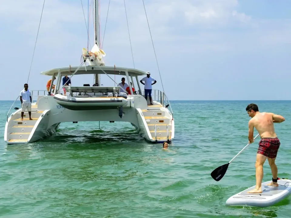 Catamaran and paddleboarder in clear tropical water