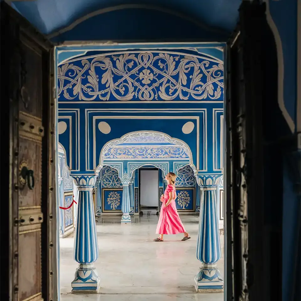 Solo woman walking through the blue-painted rooms of an Indian palace